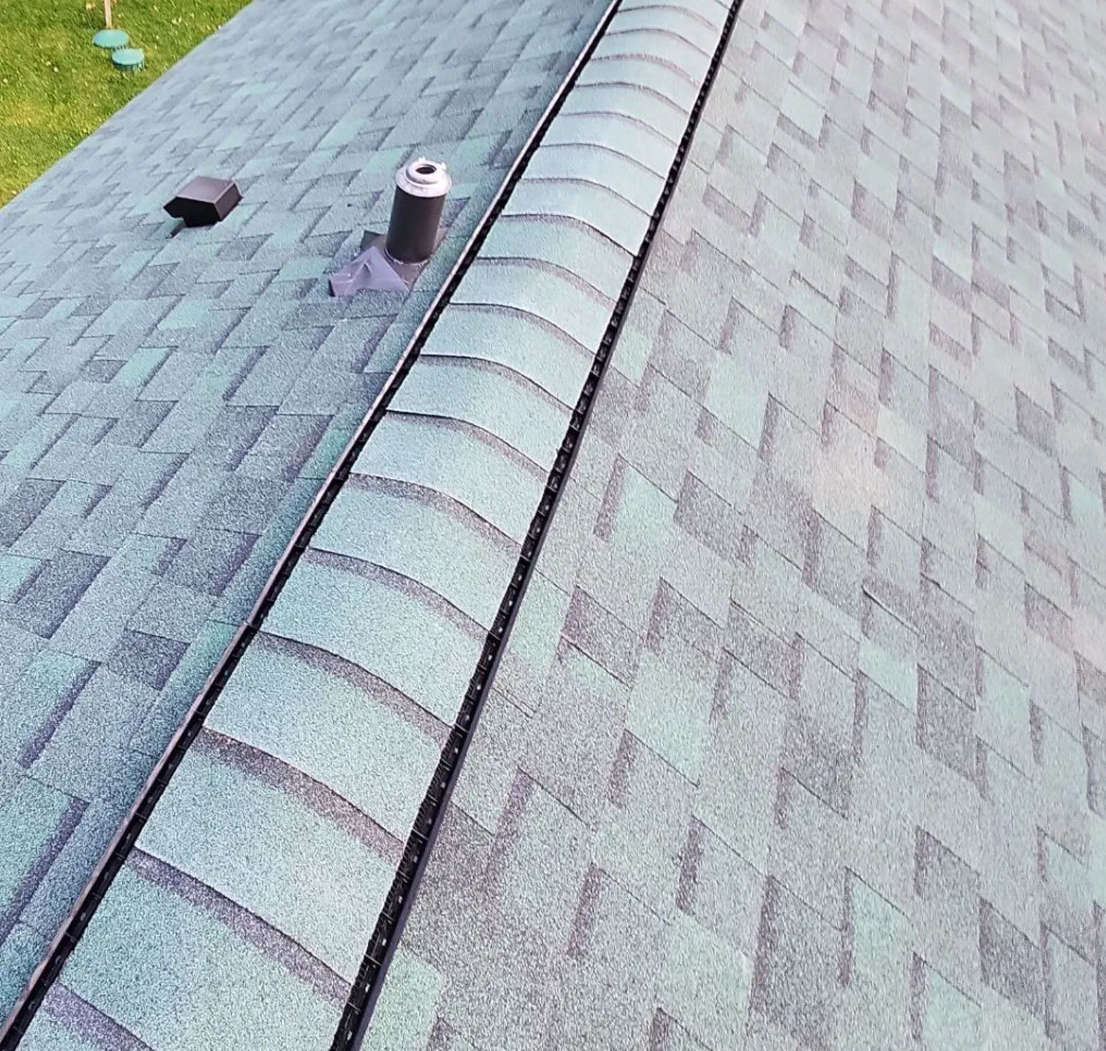Finished asphalt shingle roof replacement with ridge cap shingles and roof penetrations