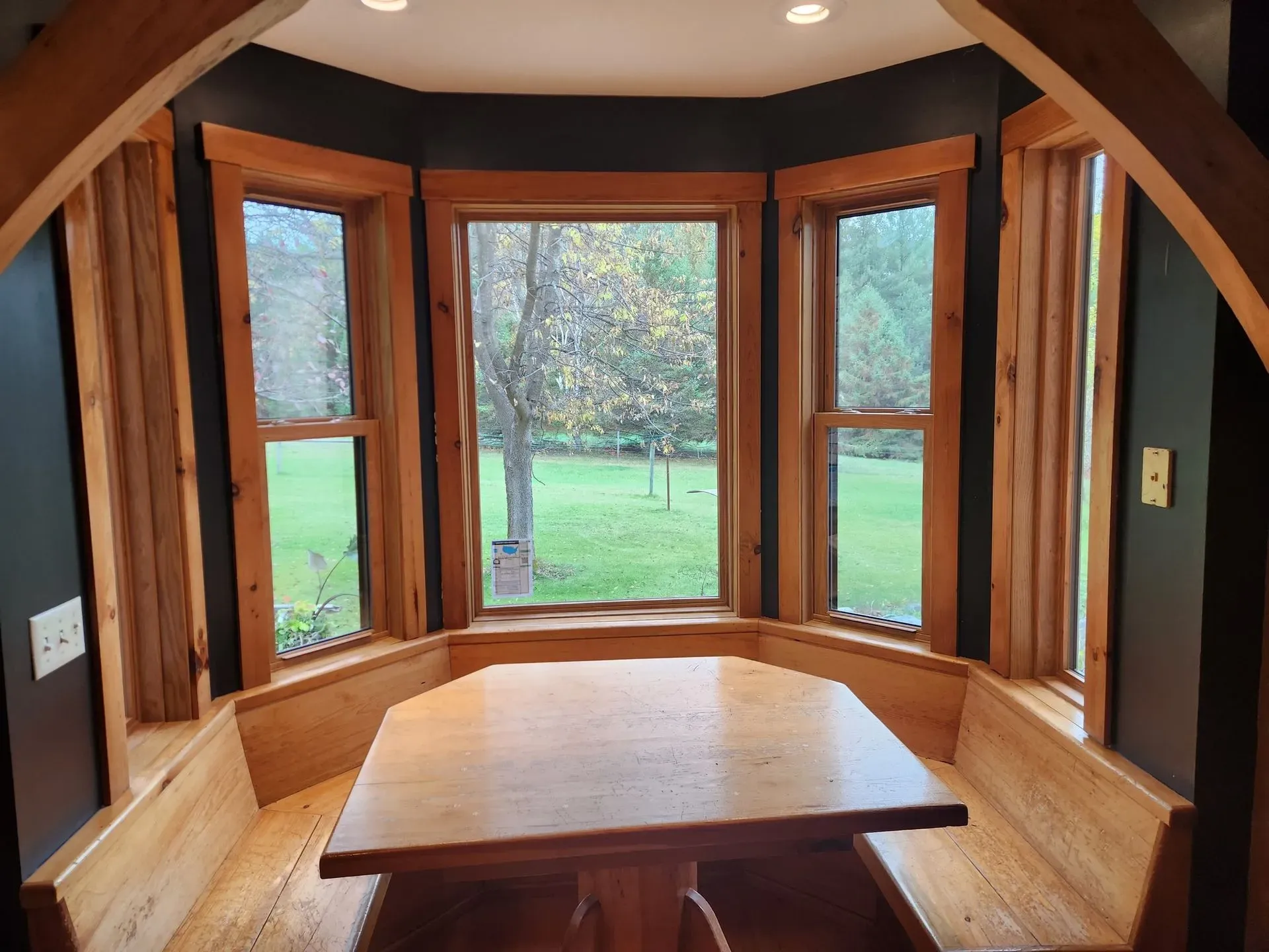 Completed bay window replacement with large glass panels and natural wood interior trim