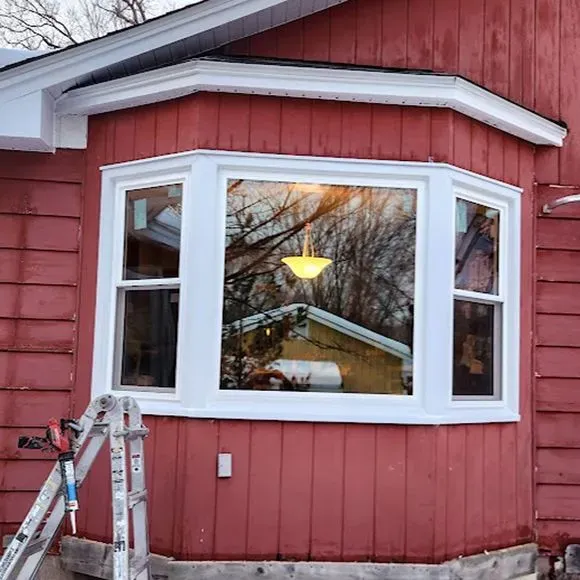 Large white bay window repair on a home with red exterior siding