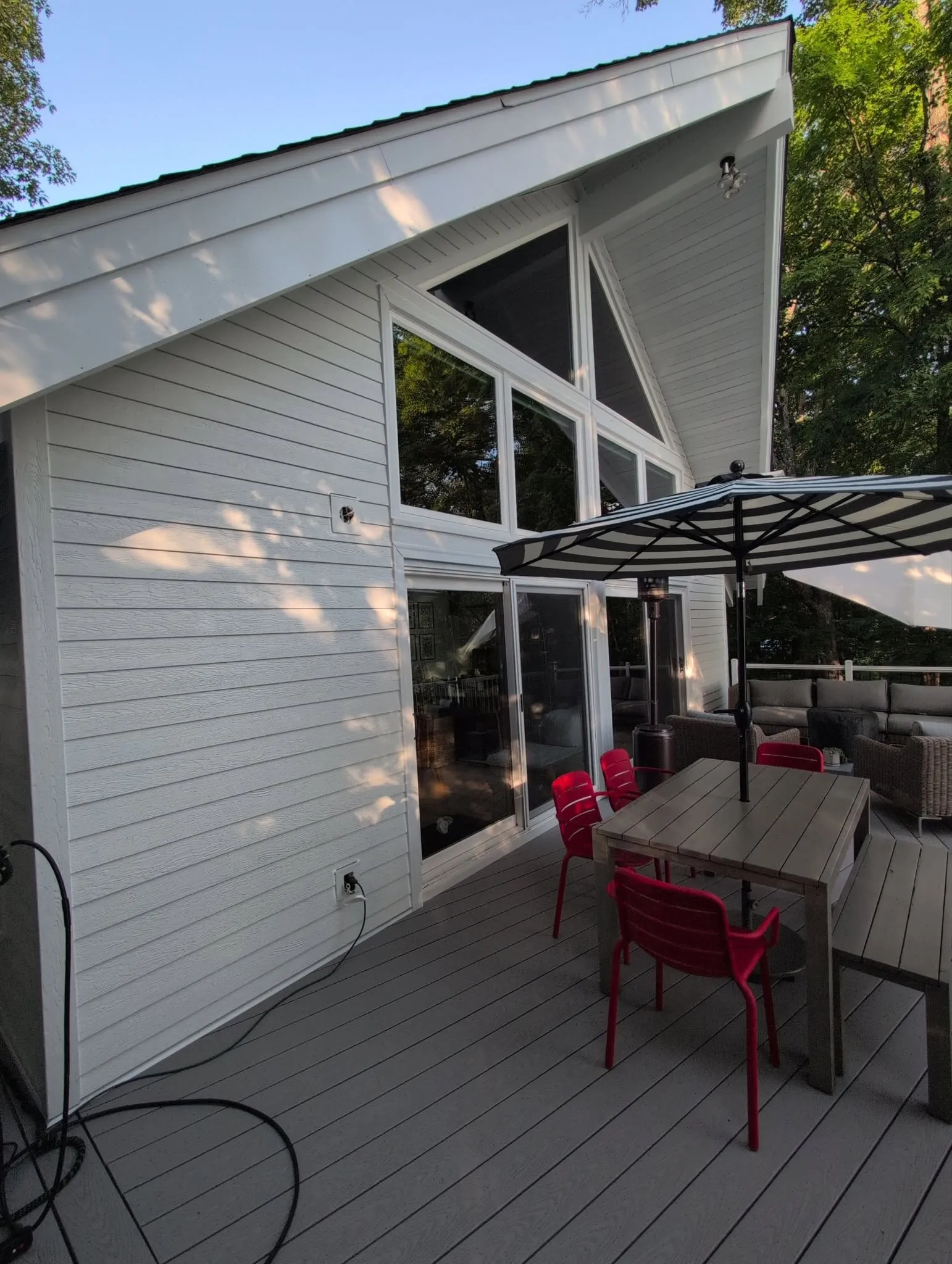 Completed full siding replacement with white horizontal siding around large windows and a deck