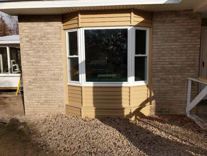 Completed bay window replacement with white frames on a brick home